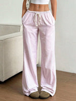 Person wearing light pink striped pajama pants in a room with a beige couch.