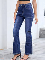 Person wearing blue flared jeans standing on a stone floor with a white wall background