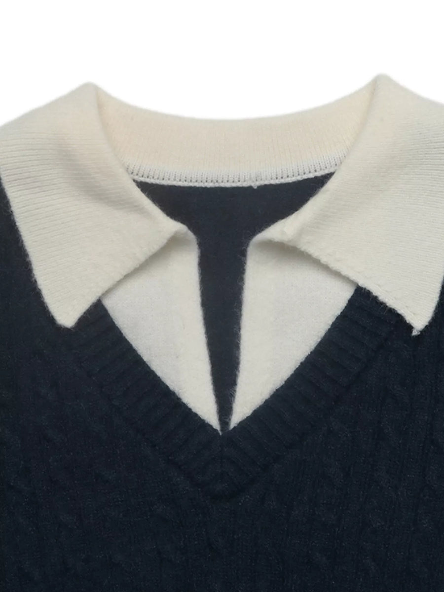 Close-up of a knit sweater with a dark navy body and a contrasting cream collar, showing the ribbed texture and V-neckline.