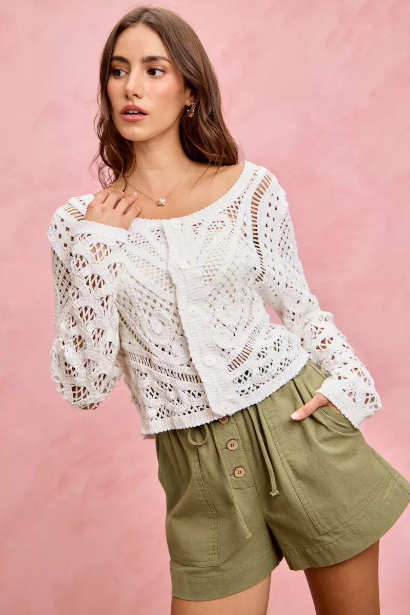 Woman wearing a white lace top and green shorts against a pink background