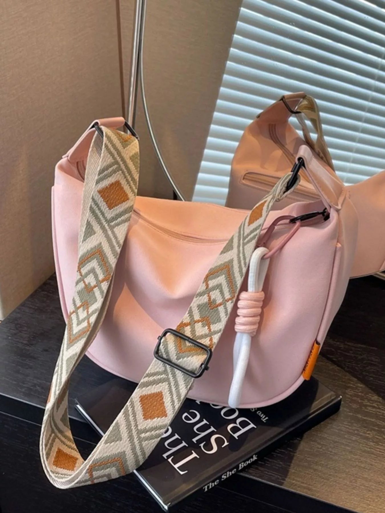 Pink bag with a patterned strap on a surface