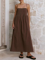 Woman wearing a brown dress standing against a stone wall.