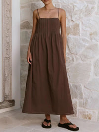 Woman wearing a brown dress standing against a stone wall.