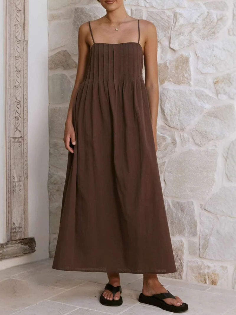 Woman wearing a brown dress standing against a stone wall.