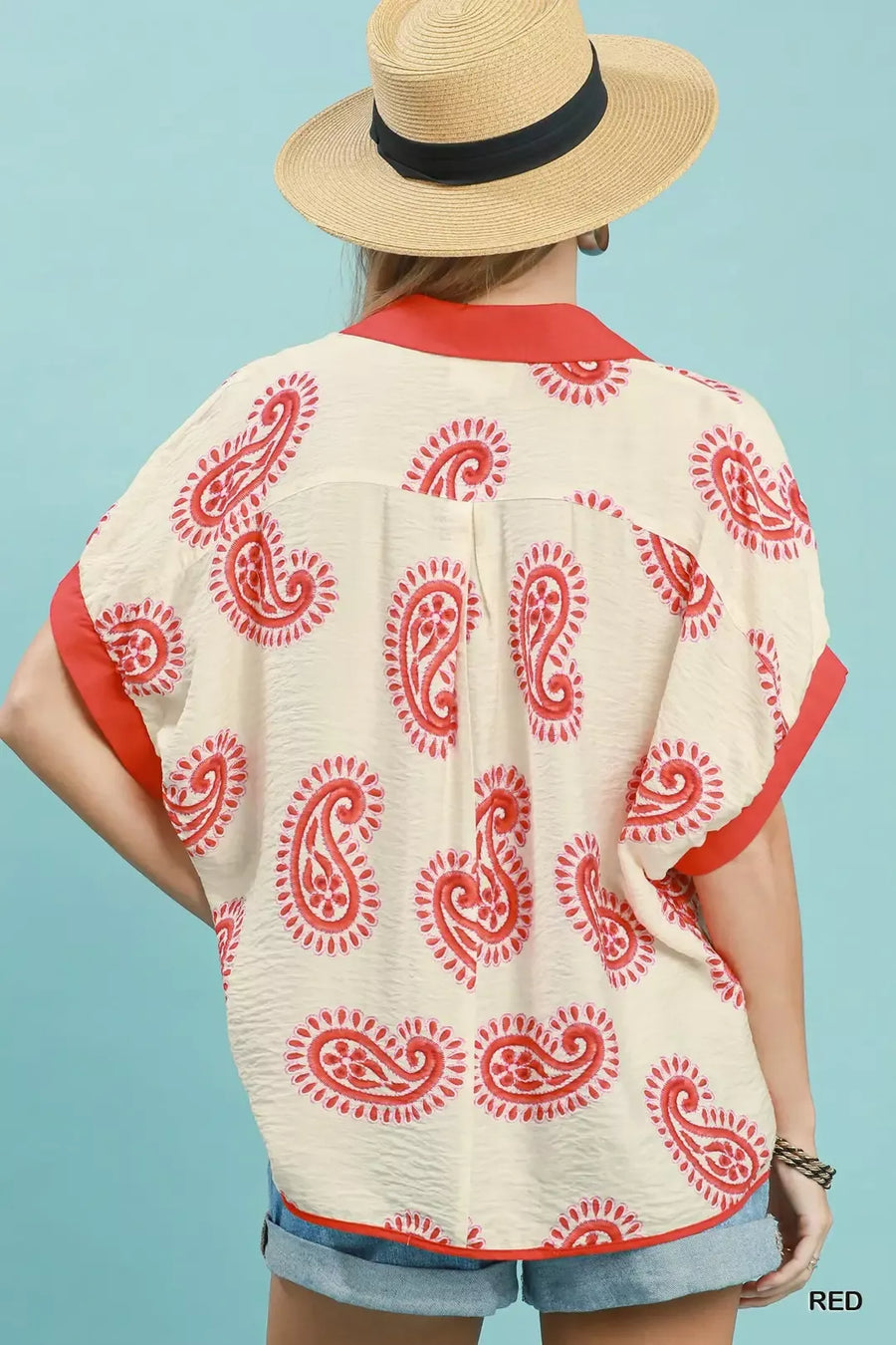 Person wearing a red and white patterned kimono-style top with denim shorts against a light blue background.