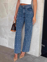 Person wearing blue jeans with white polka dots against a tiled wall.