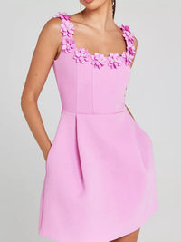 Pink dress with floral straps on a gray background