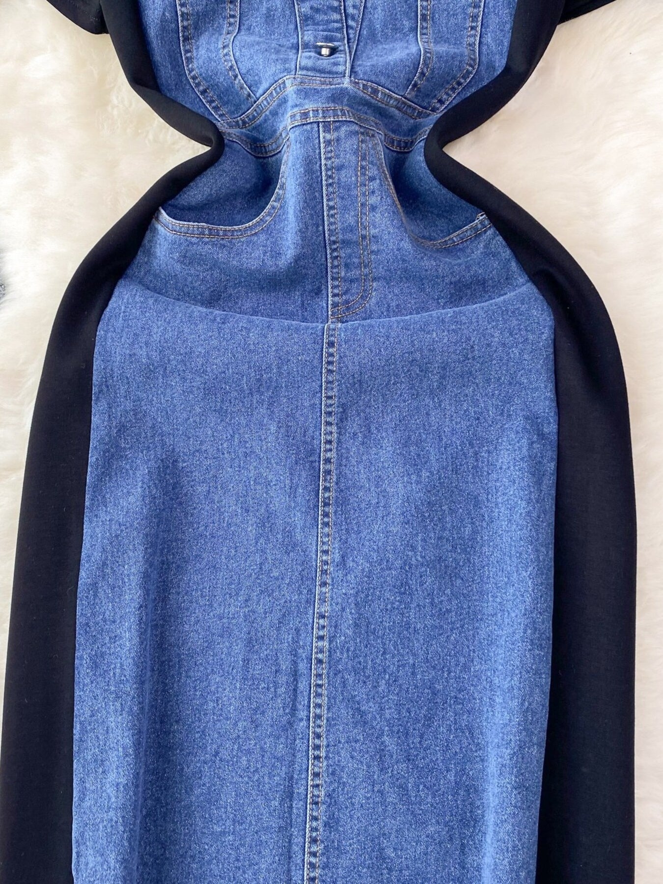Blue denim dress with black hood on a beige background