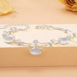 Silver bracelet with leaf-shaped charms on a beige background