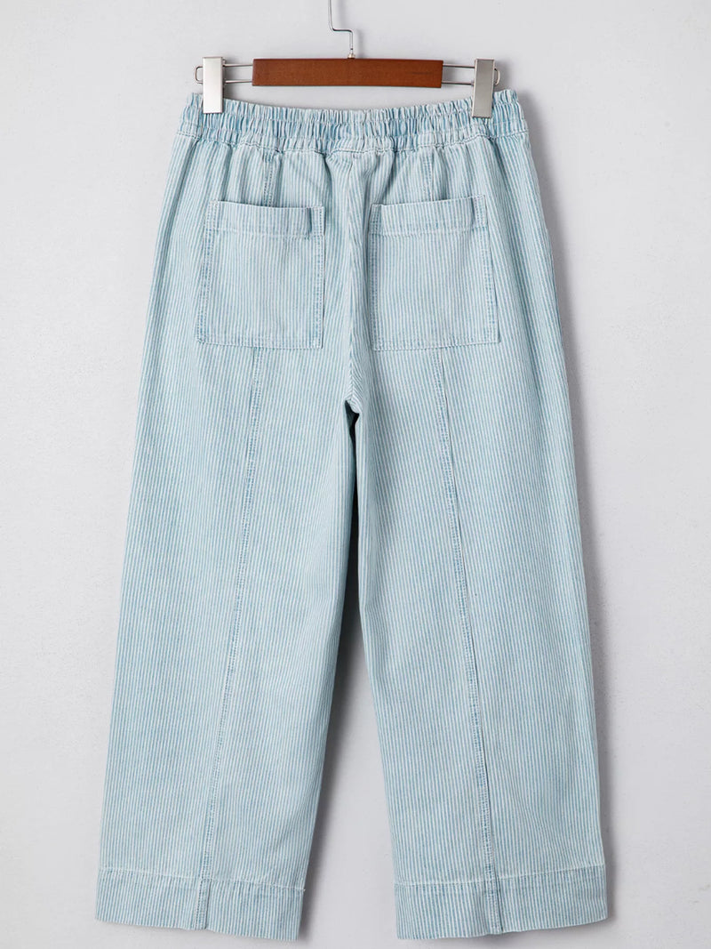 Light blue striped pants on a hanger against a white background