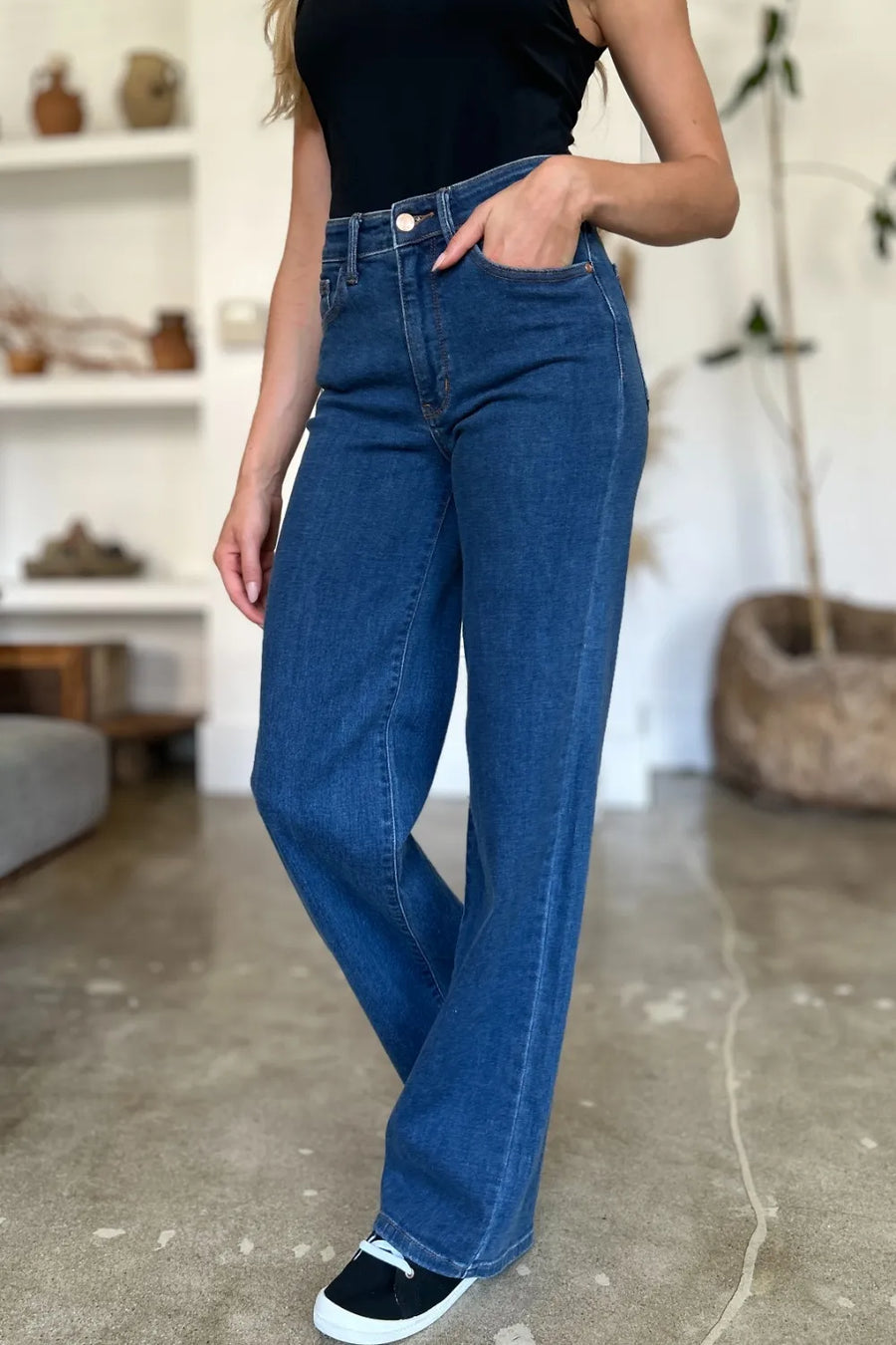 Person wearing blue jeans and a black top in an indoor setting