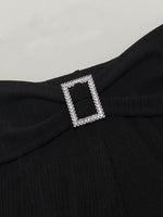 Black garment with a decorative silver buckle on a light gray background