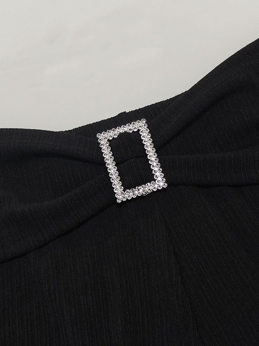 Black garment with a decorative silver buckle on a light gray background