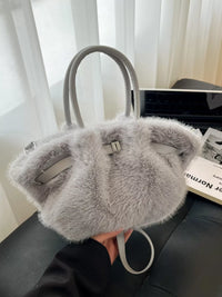 Gray fur handbag with a visible brand tag on a dark surface.