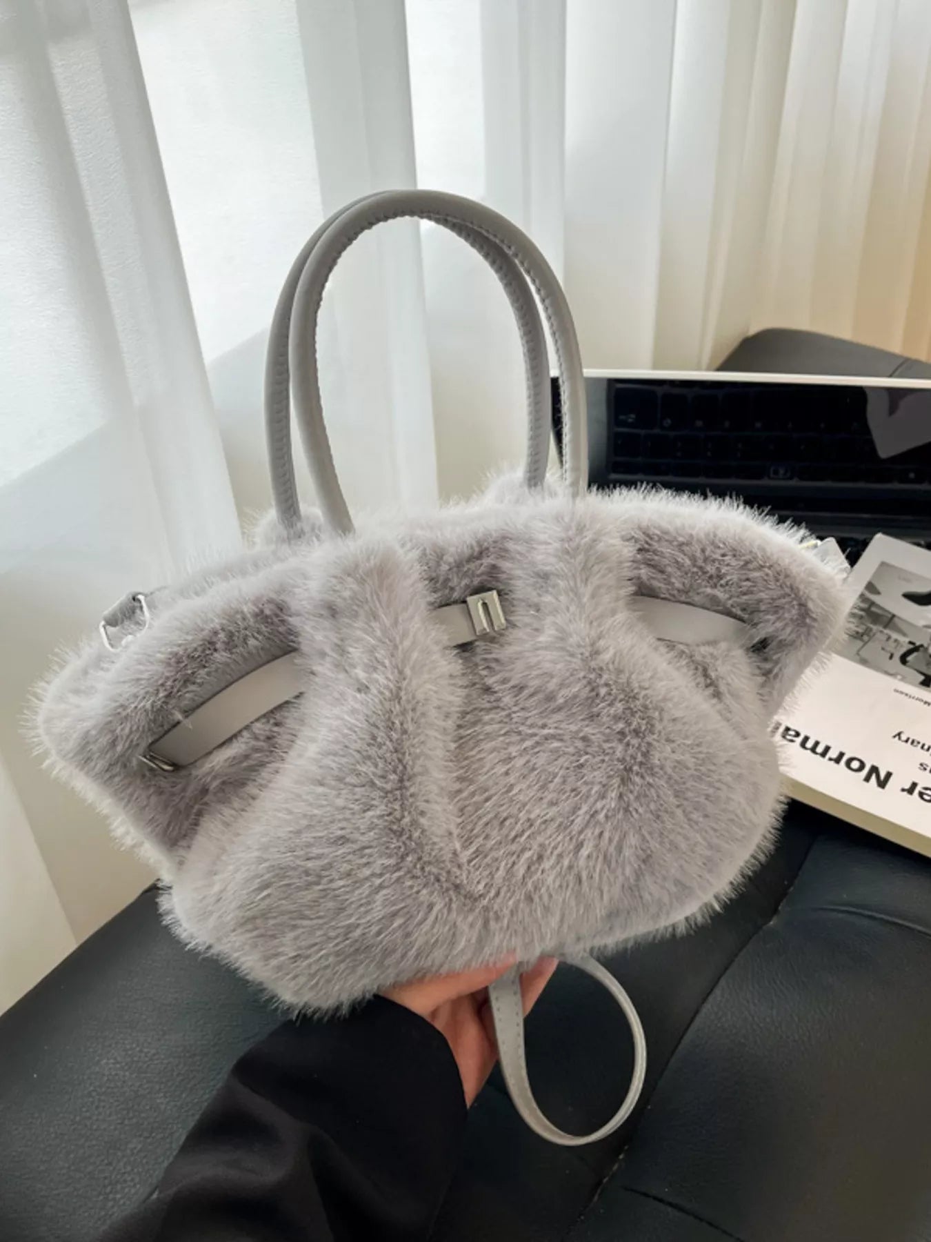 Gray fur handbag with a visible brand tag on a dark surface.
