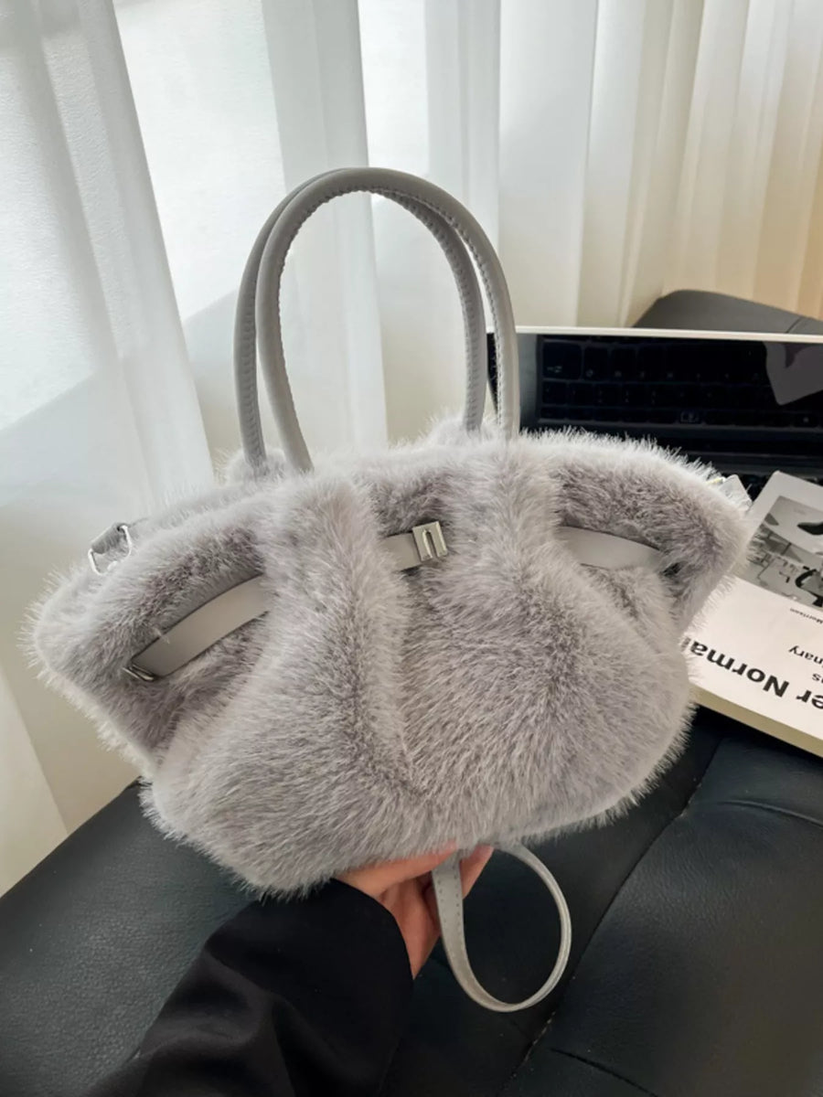 Gray fur handbag with a visible brand tag on a dark surface.