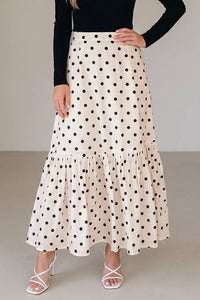 Woman wearing a polka dot skirt with a plain background