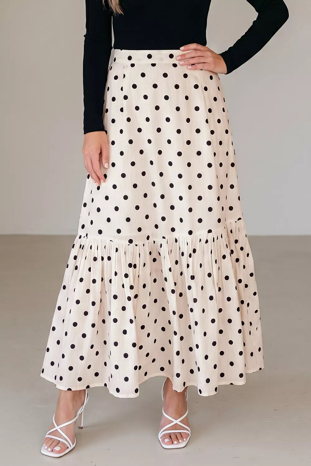 Woman wearing a polka dot skirt with a plain background
