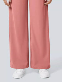 Pink wide-leg pants worn with white sneakers on a light gray background