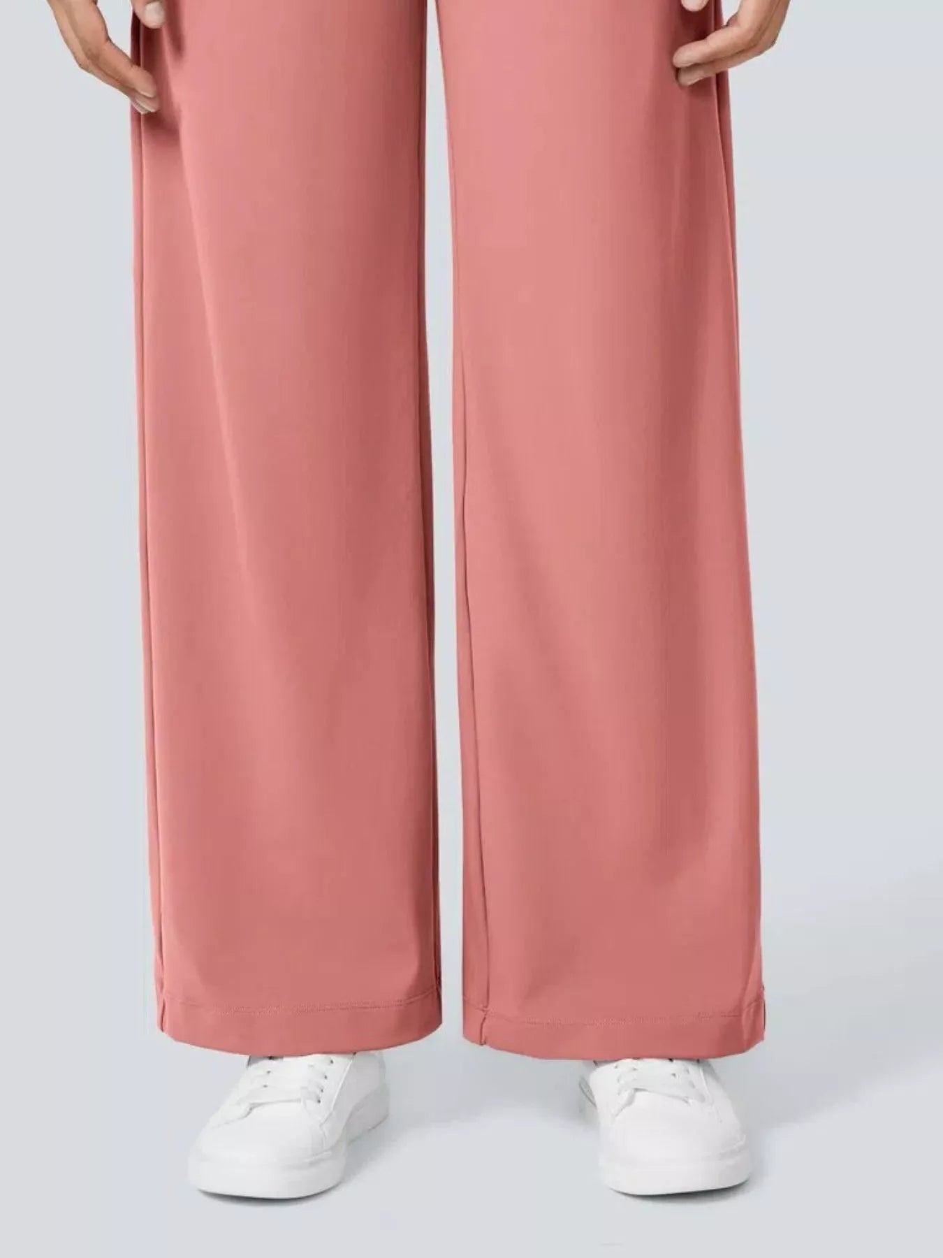 Pink wide-leg pants worn with white sneakers on a light gray background