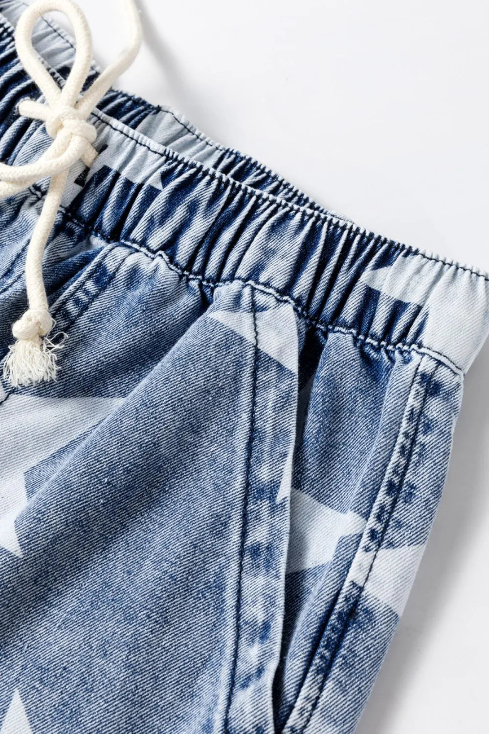 Close-up of denim shorts with a white drawstring on a white background
