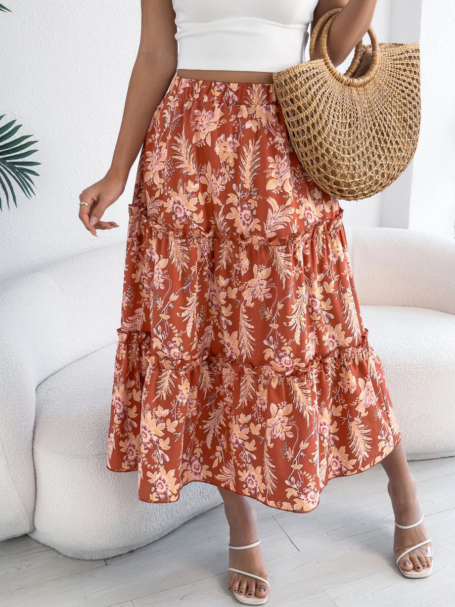 Person wearing a floral skirt and holding a straw bag indoors.