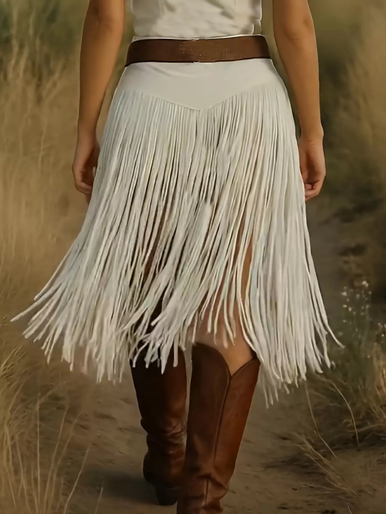 Person wearing a white fringe skirt and brown boots in a natural setting