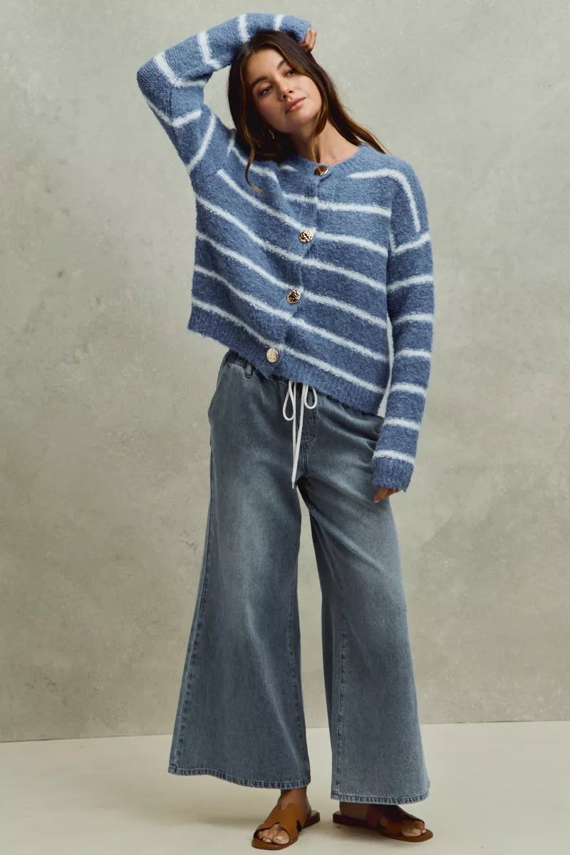 Woman wearing a blue and white striped sweater and jeans against a neutral background