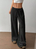 Person wearing dark wide-leg pants with a plain background