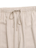 Beige linen pants with drawstring waistband on a matching fabric background