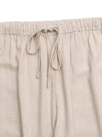 Beige linen pants with drawstring waistband on a matching fabric background