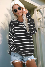 Woman wearing a black and white striped sweater and denim shorts outdoors.