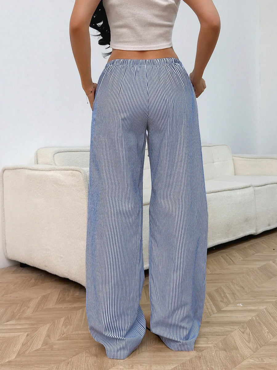 Person wearing blue and white striped pants in a room with a beige sofa.