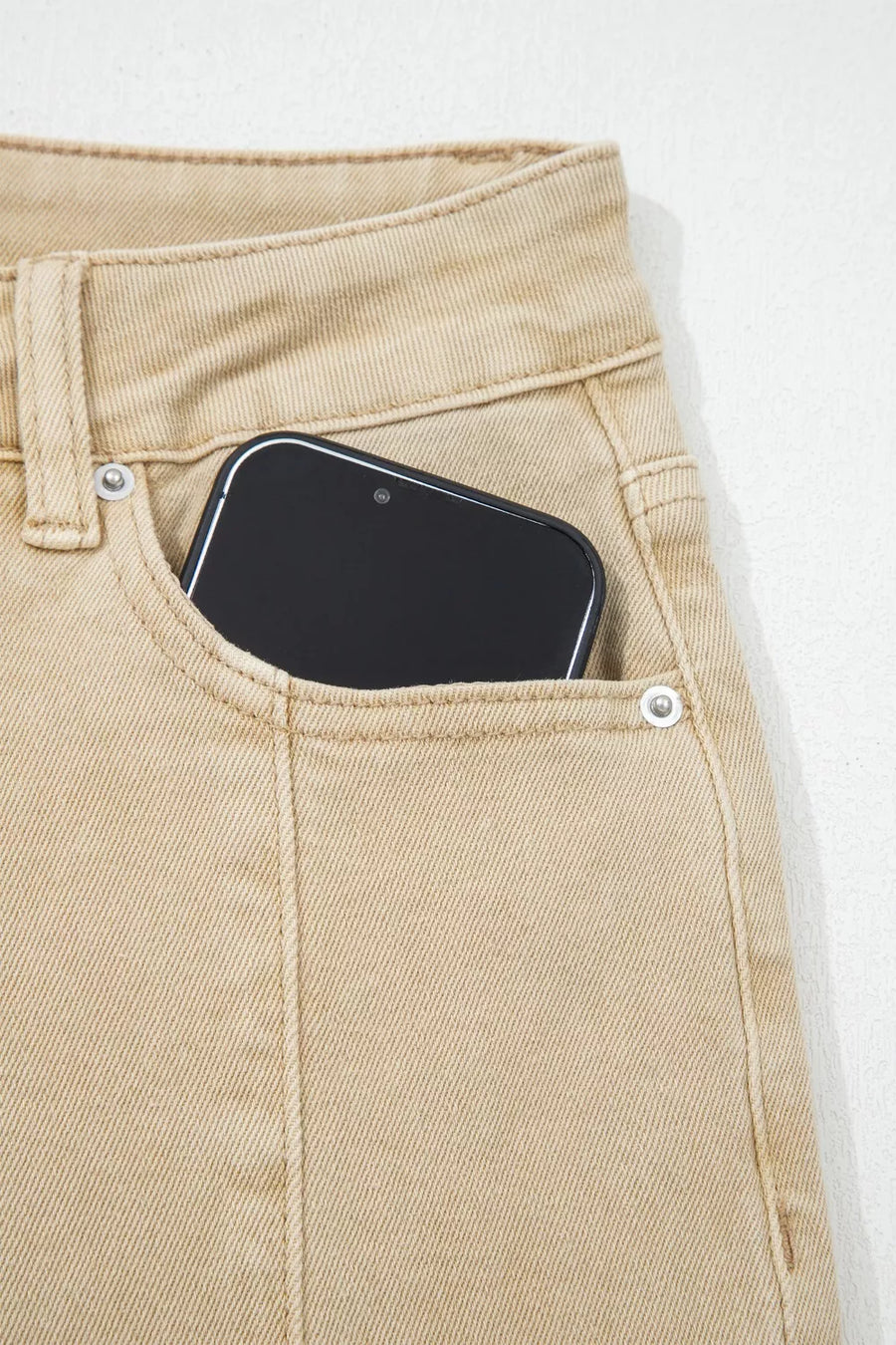 Phone in a pocket of beige pants on a white background