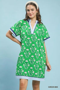 Woman wearing a green dress with white patterns on a light blue background