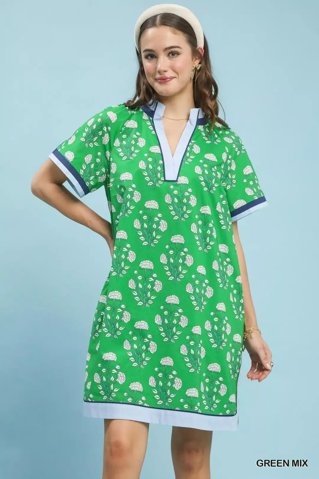 Woman wearing a green dress with white patterns on a light blue background