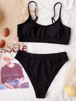 Black bikini set on a textured surface with a magazine underneath