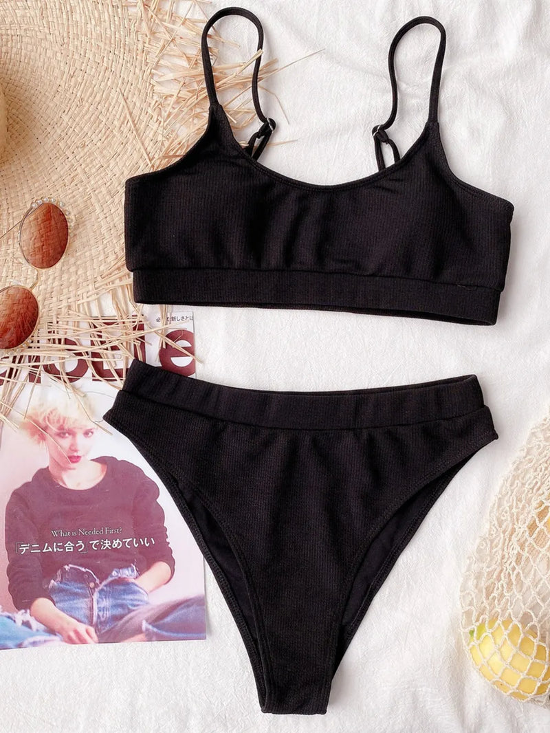 Black bikini set on a textured surface with a magazine underneath