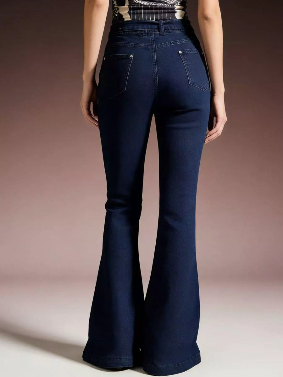 Navy blue flared jeans worn by a person on a plain background