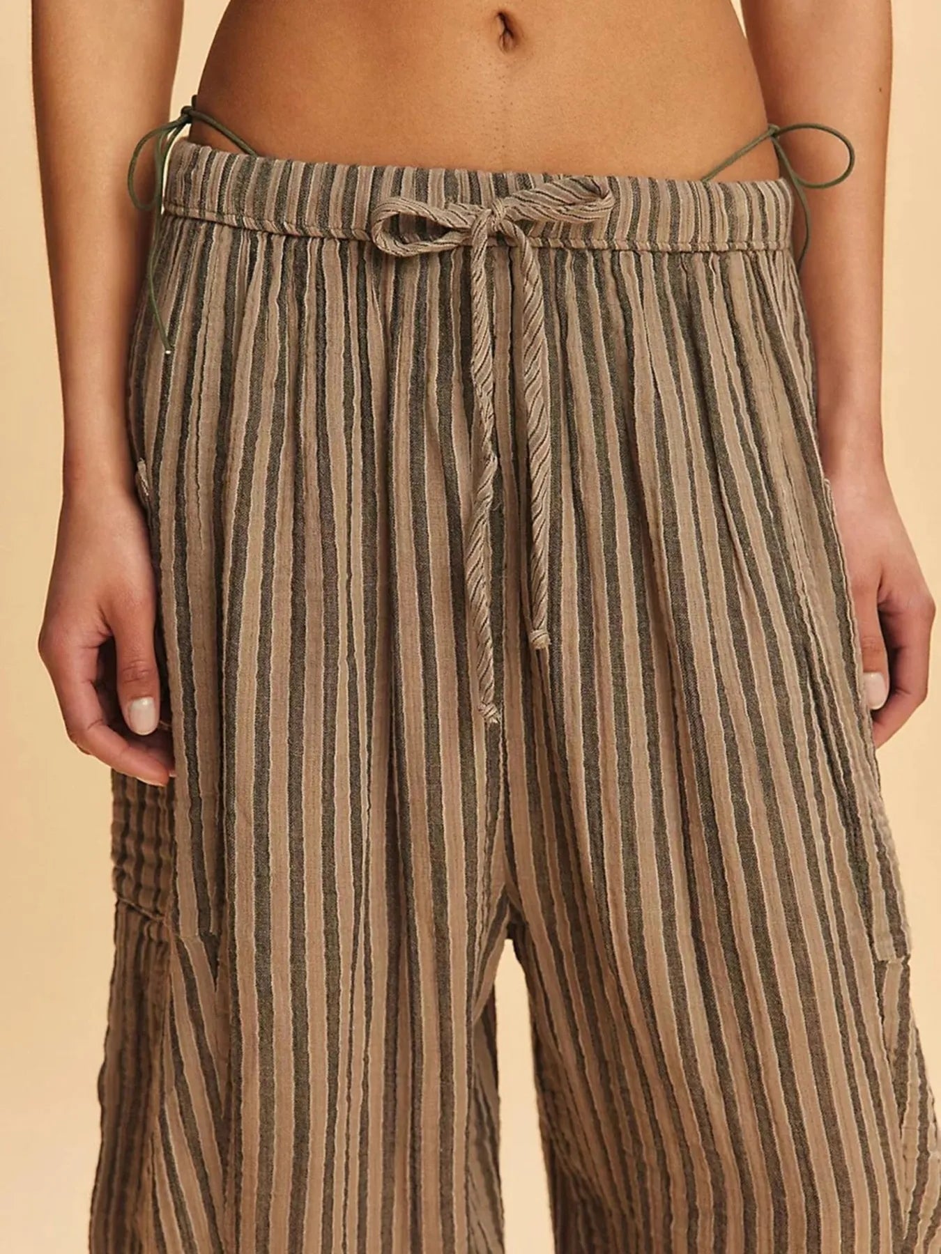 Striped pants with a drawstring waist on a beige background