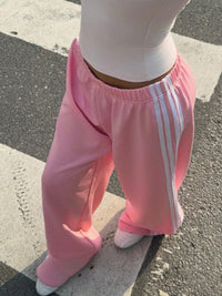 Person wearing pink Adidas tracksuit pants on a street