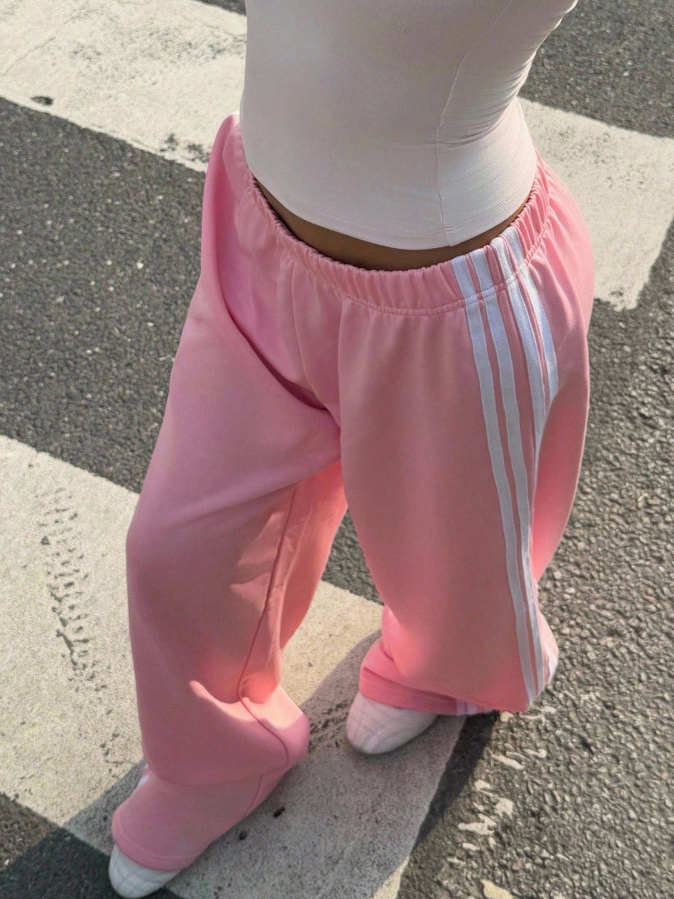 Person wearing pink Adidas tracksuit pants on a street