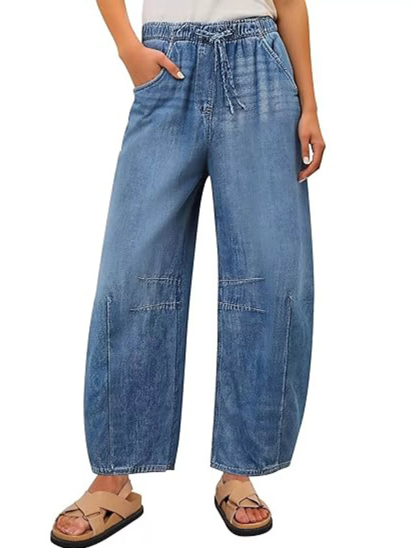 Wide-leg blue jeans worn by a person on a white background