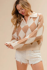 Woman wearing a beige and white diamond patterned sweater with white shorts on a beige background