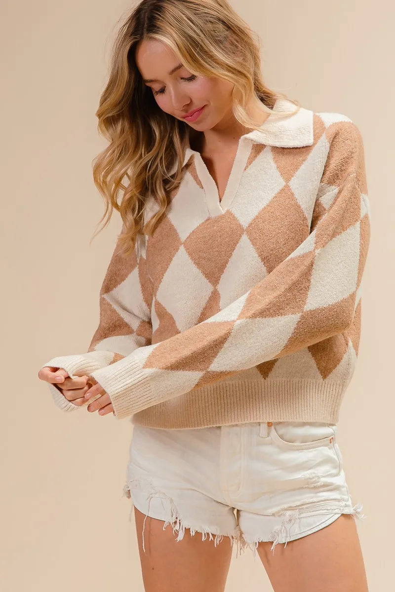 Woman wearing a beige and white diamond patterned sweater with white shorts on a beige background