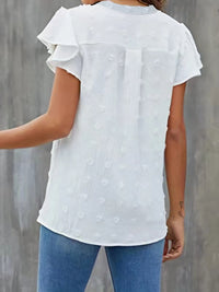 White blouse with ruffled sleeves worn by a person against a gray background