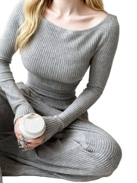 Person wearing a gray ribbed sweater holding a white cup on a white background