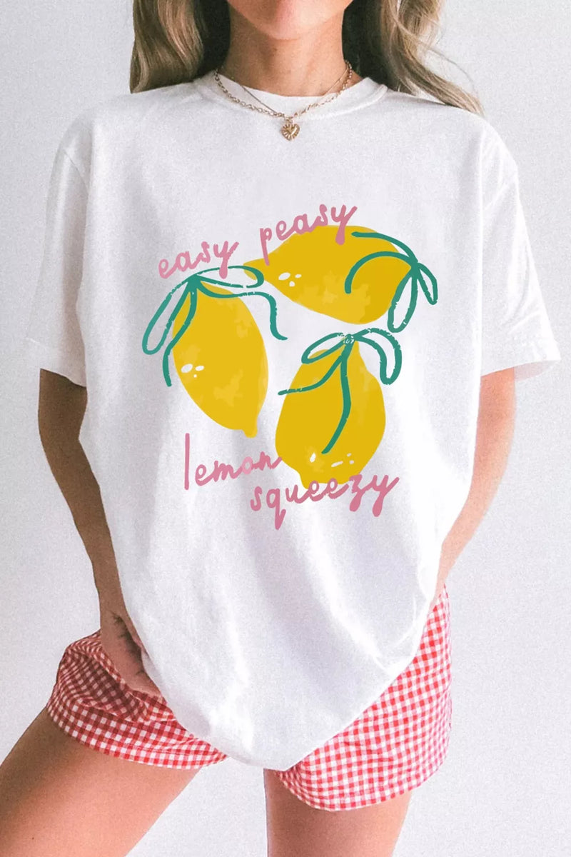 Person wearing a white t-shirt with lemon graphics and text, paired with red and white checkered shorts on a plain background.