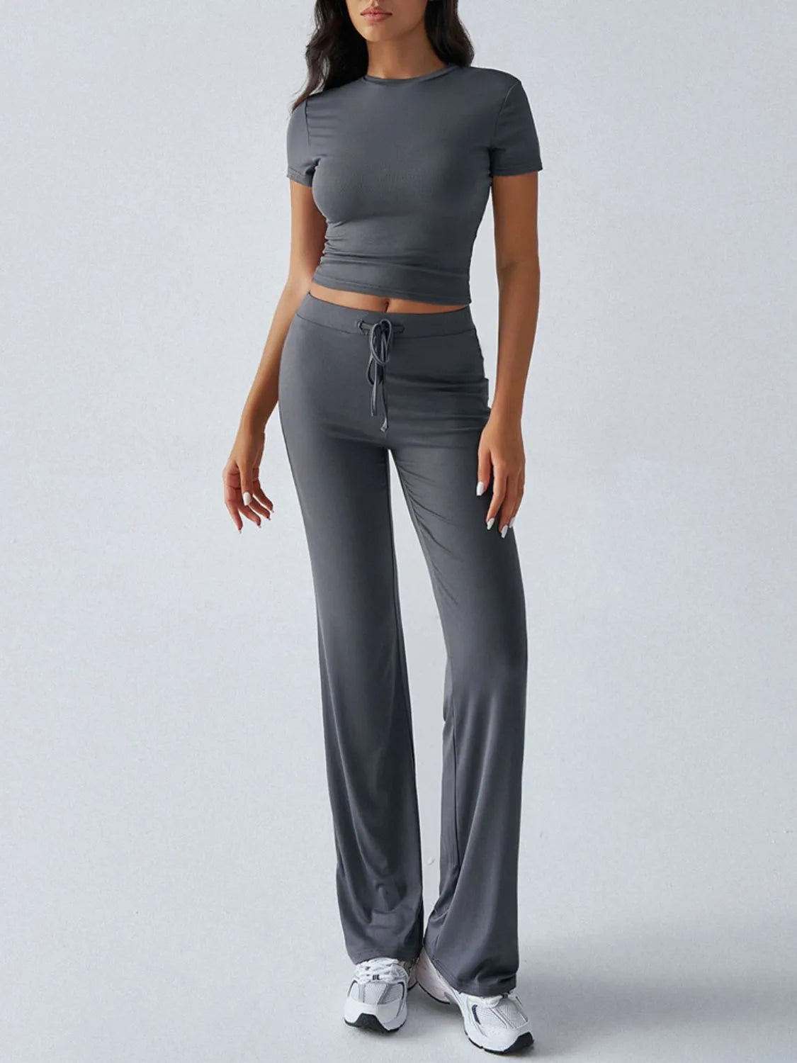 Woman wearing a gray athletic outfit on a light gray background