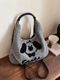 Gray textured handbag with black paw print design on a wooden surface.